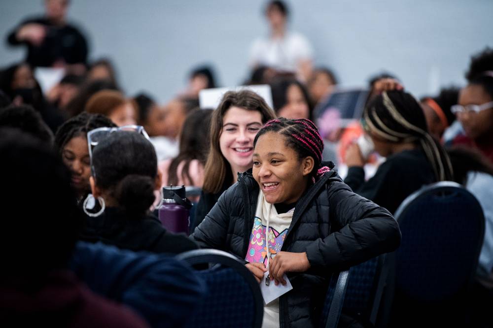 Girls of Color Summit previous event with a student giggling with friends